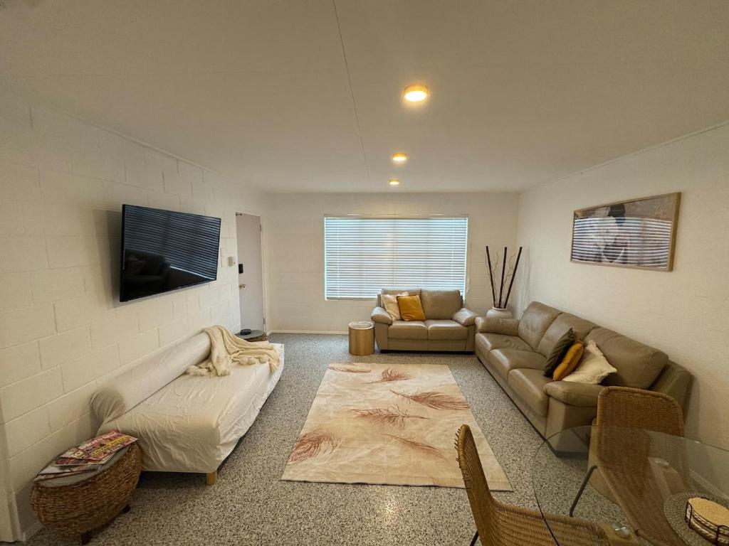 a living room with two couches and a tv at Large Earthy toned Apartment in Ross River