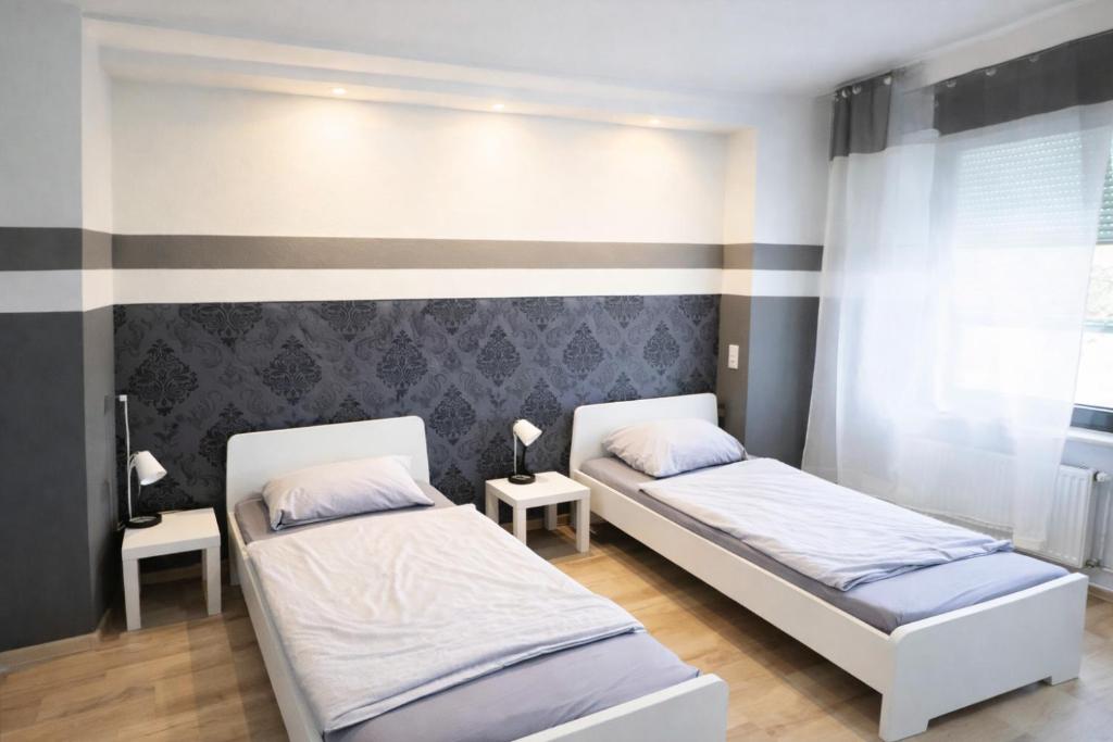 2 Betten in einem Zimmer mit 2 Tischen in der Unterkunft 4RENT Apartments - Monteurzimmer in Worms