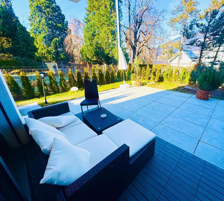 a white couch sitting on a patio with a chair at Villa Lakeview Appartment in Leissigen