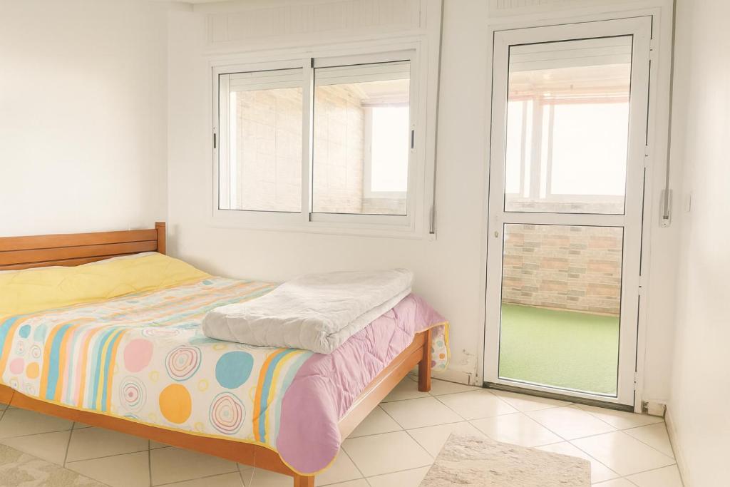 a bedroom with a bed and two windows at Miss ALIA Aéroport in Tangier