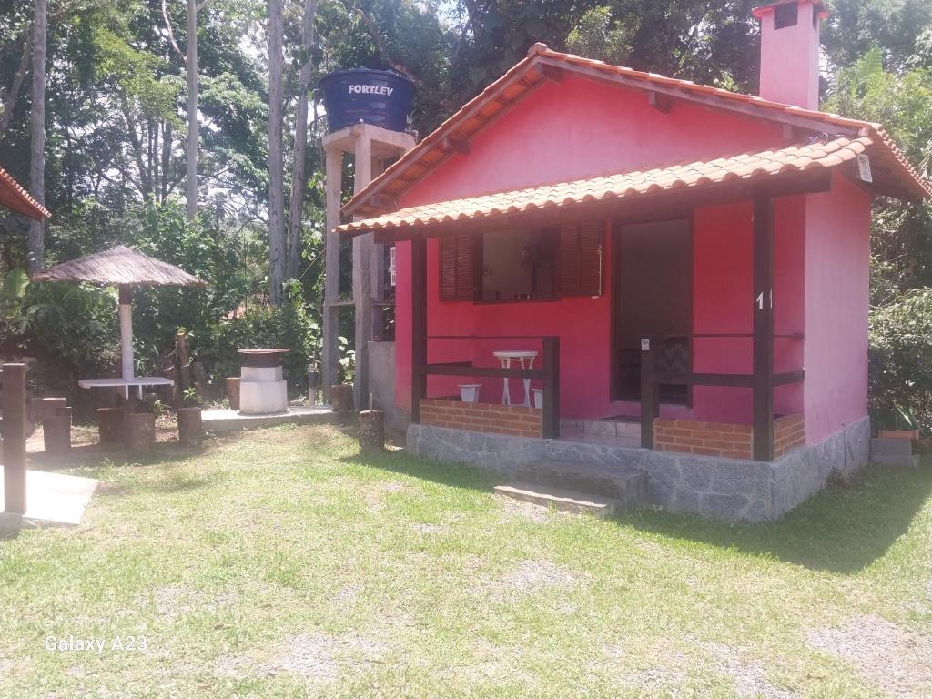 a small red building in a yard with a table at Morada do Sabiá - chalé 1 in Resende