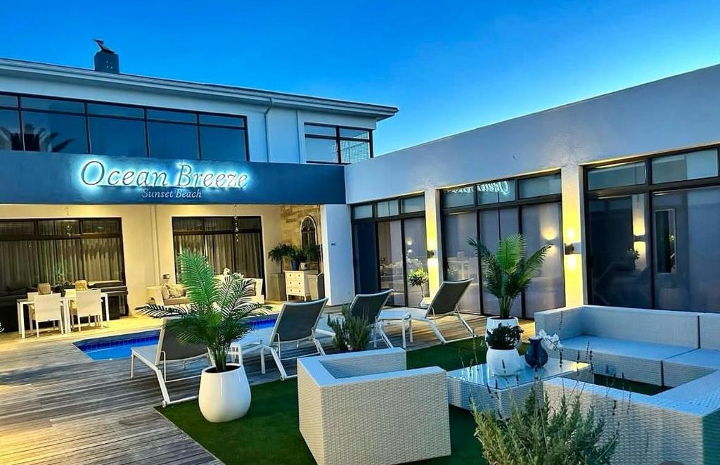 a building with a patio with chairs and tables at OCEAN BREEZE SUNSET BEACH - Boutique Guesthouse - Cape Town in Cape Town