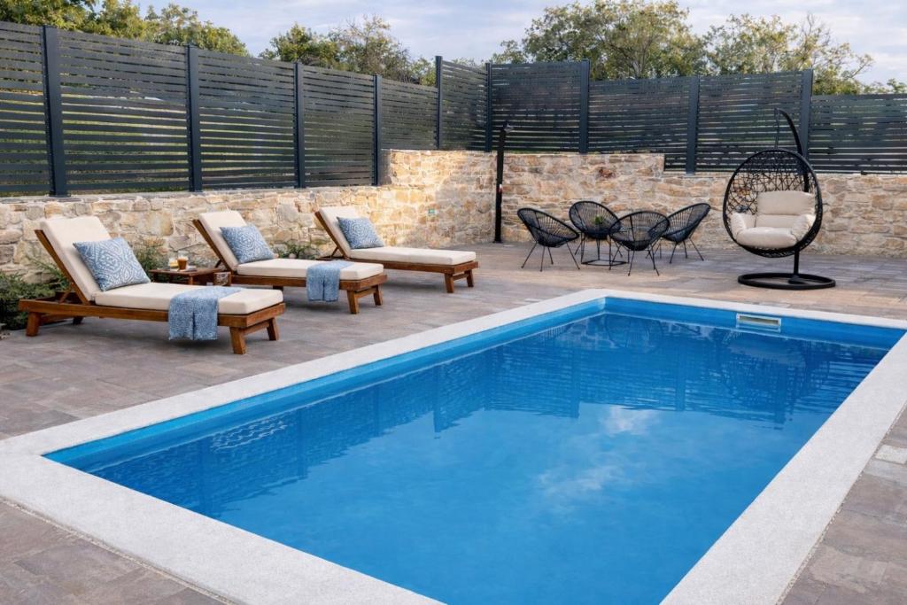 ein Swimmingpool mit Stühlen und eine Terrasse mit Tisch und Stühlen in der Unterkunft House Gruja with Pool in Primošten