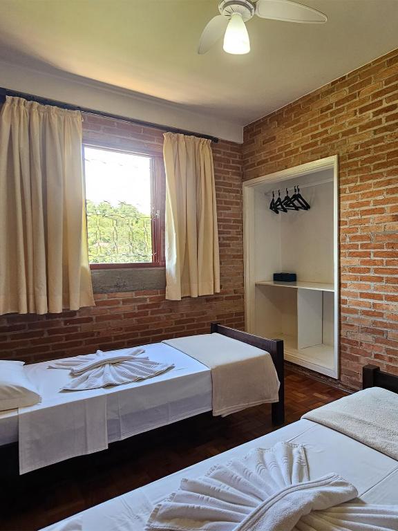 a bedroom with two beds and a brick wall at Pousada Siloé - Mosteiro de São Bento em Vinhedo in Vinhedo