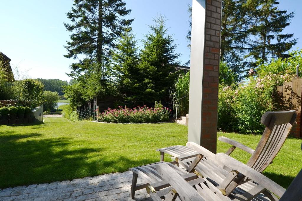 two wooden chairs sitting in a yard with a lawn at Ferienwohnung Malerwinkel in Seedorf