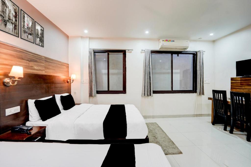 een slaapkamer met een wit en zwart bed en ramen bij Collection O Prem Nagar Dehradun Formerly Hotel Parjaat Residency in Dehradun