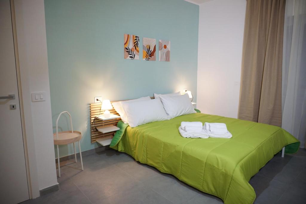 a bedroom with a green bed with two towels on it at Farina Apartments in San Nicola La Strada