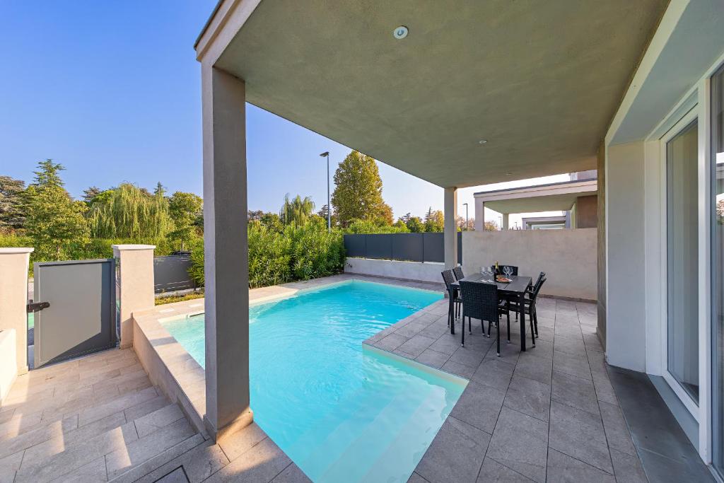 - une piscine avec une table et des chaises à côté d'une maison dans l'établissement Villa Prestige, à Sirmione