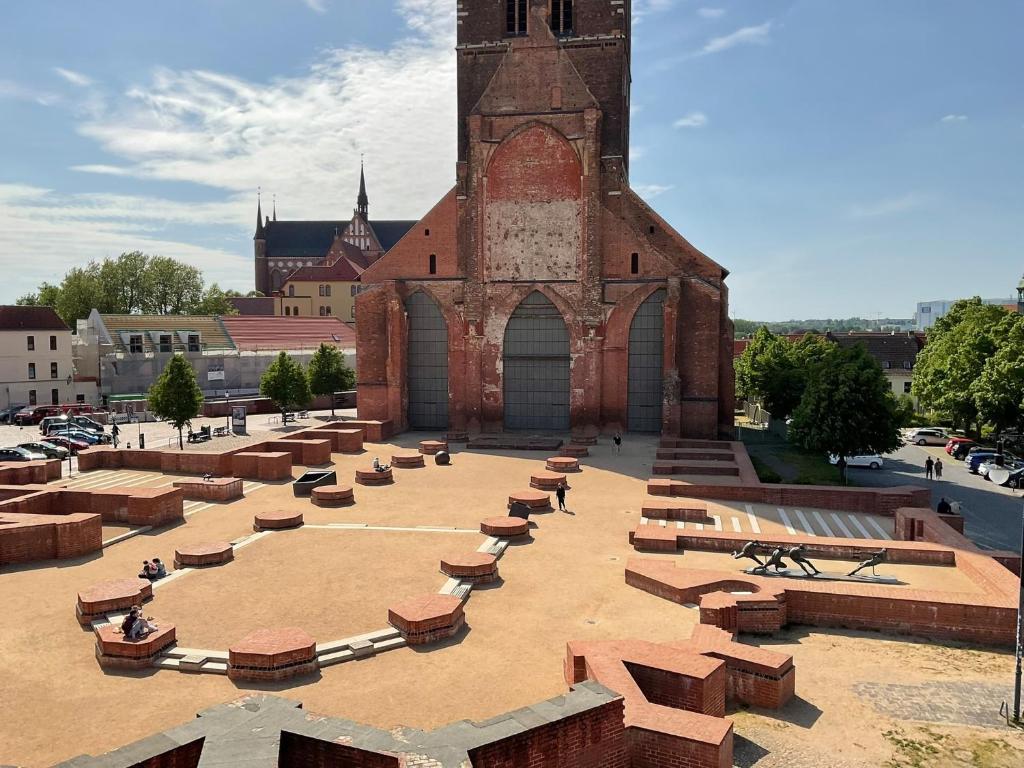 a building with a clock tower with benches in front of it at Marienkirche 1 - ABC335 in Wismar