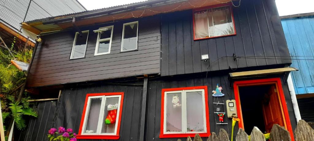 a black house with red doors and windows at Casa familiar chana 388 in Puerto Montt