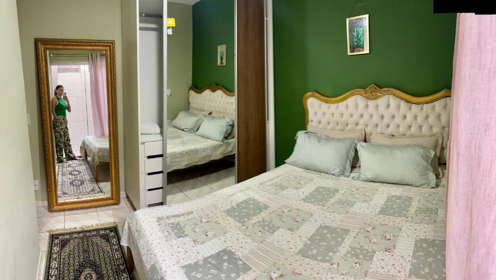 een vrouw die een foto neemt van een slaapkamer met een bed bij Casa verde 4 quartos in Goiânia