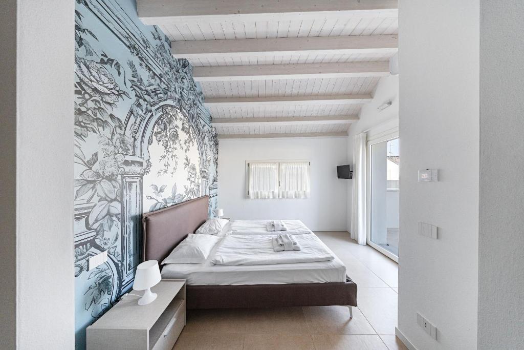 - une chambre avec un lit et un mur orné d'une fresque murale dans l'établissement Villa Prestige, à Sirmione