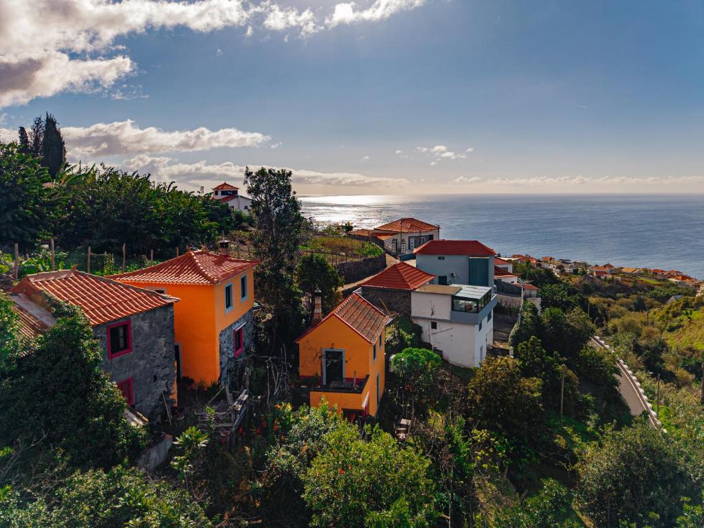 een dorp op een heuvel met de oceaan op de achtergrond bij Madeira-Meerblick-Haus in Estreito da Calheta