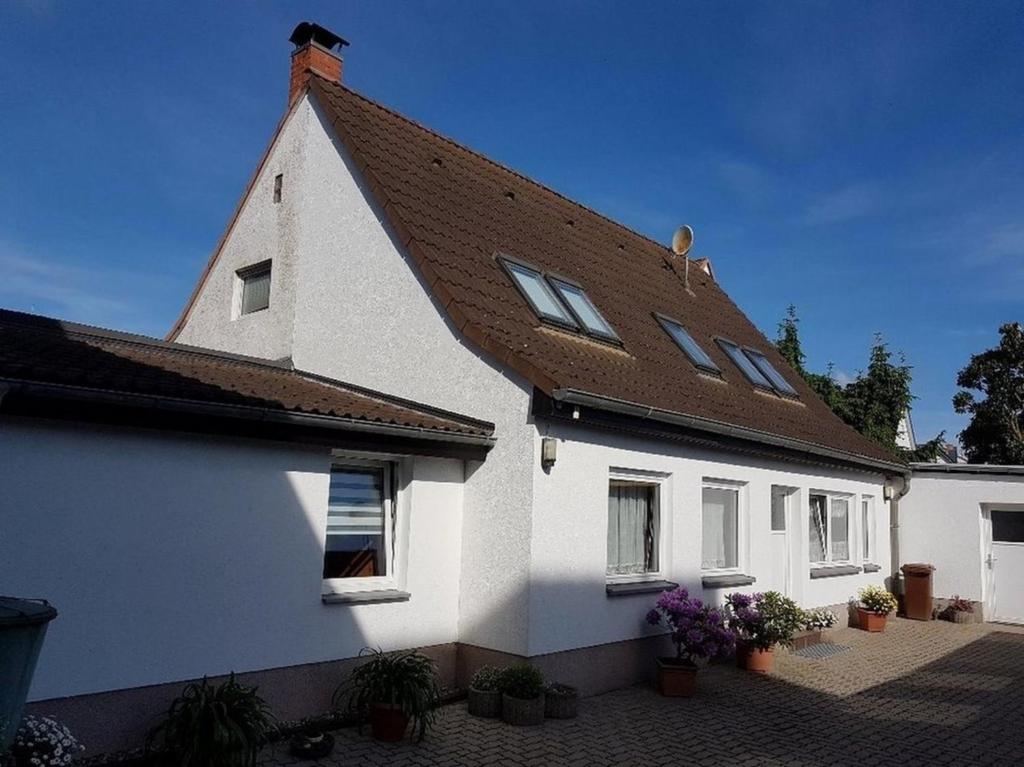 a white house with a brown roof and potted plants at Ferienhaus Thiess - ABC402 in Wismar