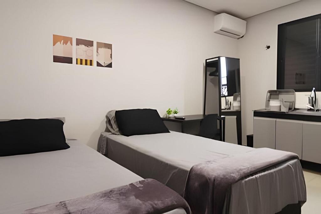 una camera con due letti e una cucina con lavandino di Studio I - Com Ar Condicionado a Jundiaí