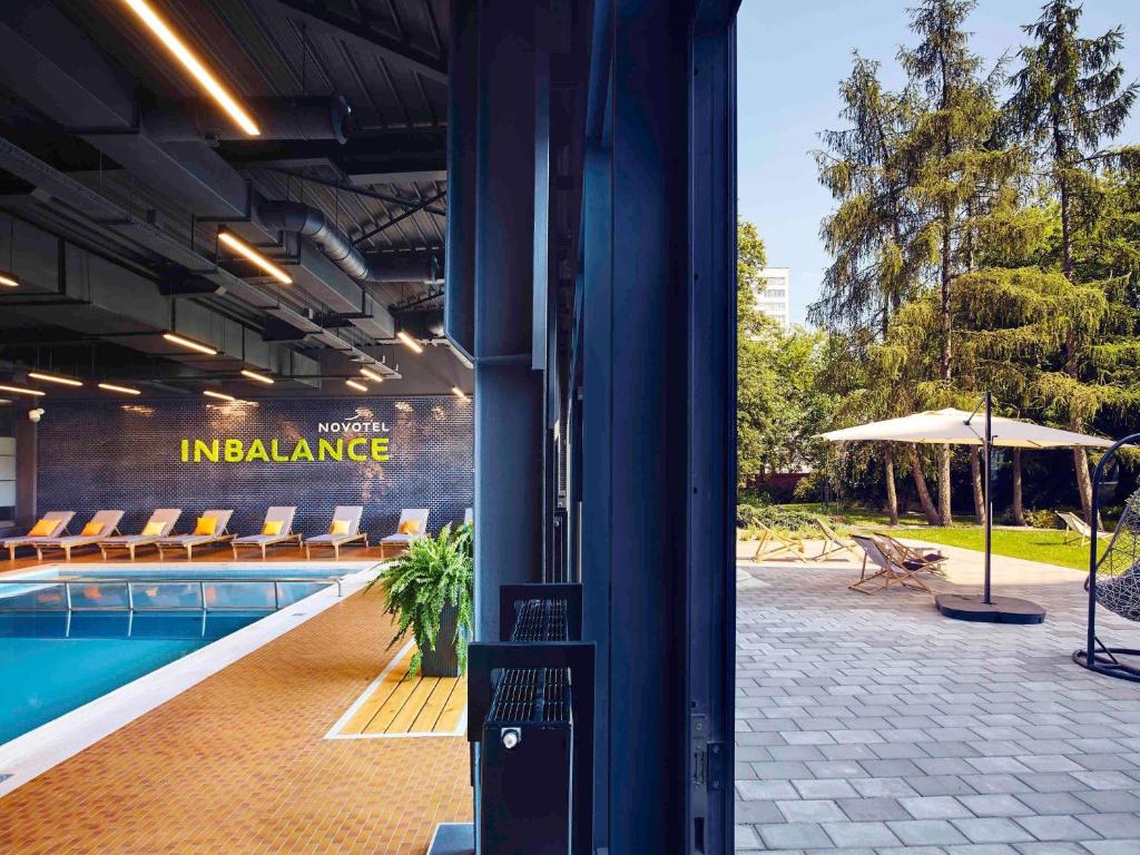 een gebouw met een zwembad met stoelen en een parasol bij Novotel Kraków City West in Krakau