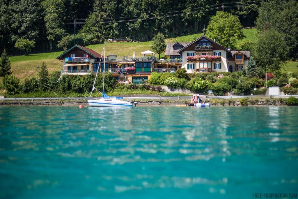 a house on the shore of a lake with a sail boat at Apartment Loindl in Unterach am Attersee