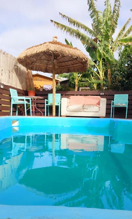 Ein Sonnenschirm und Stühle neben einem Swimmingpool in der Unterkunft On Planet in Coquimbo