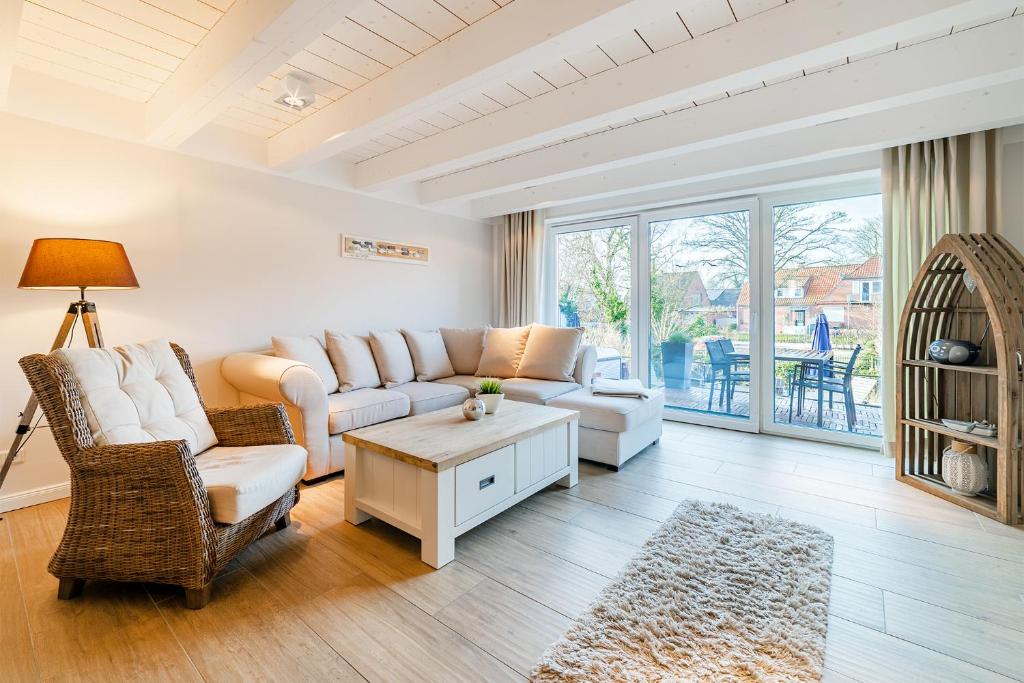 een woonkamer met een bank, stoelen en een tafel bij Haus am Siel 02 in Greetsiel