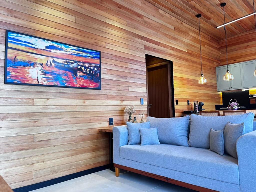 a living room with a blue couch against a wooden wall at Cabana Maciambu casa de praia Palhoça SC in Palhoça