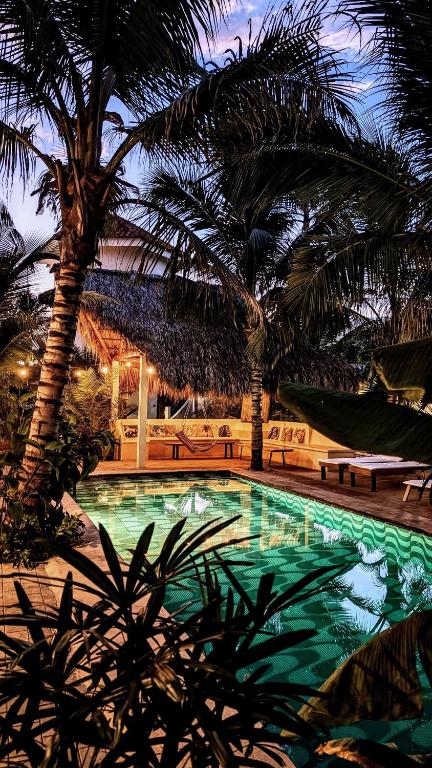 a swimming pool with palm trees in a resort at Nuevo NAYAL in Las Peñitas