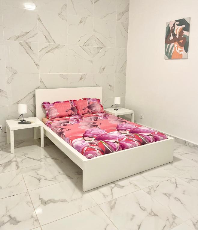 ein weißes Schlafzimmer mit einem Bett mit rosa Bettwäsche in der Unterkunft Villa Côte d Azur - 4 chambres, 4 TV, 4 salles de bain privatives - Internet Netflix in Mtsamboro