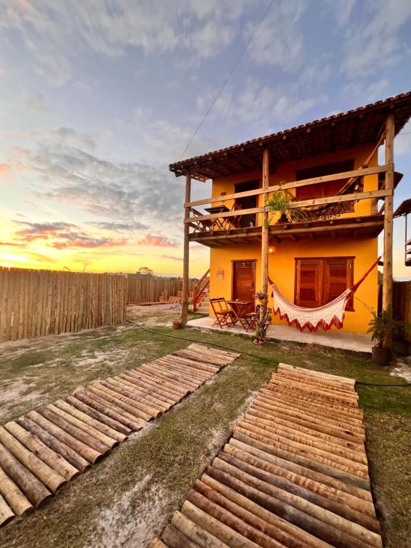 a yellow house with a fence in front of it at Chalés Calica in Caraíva