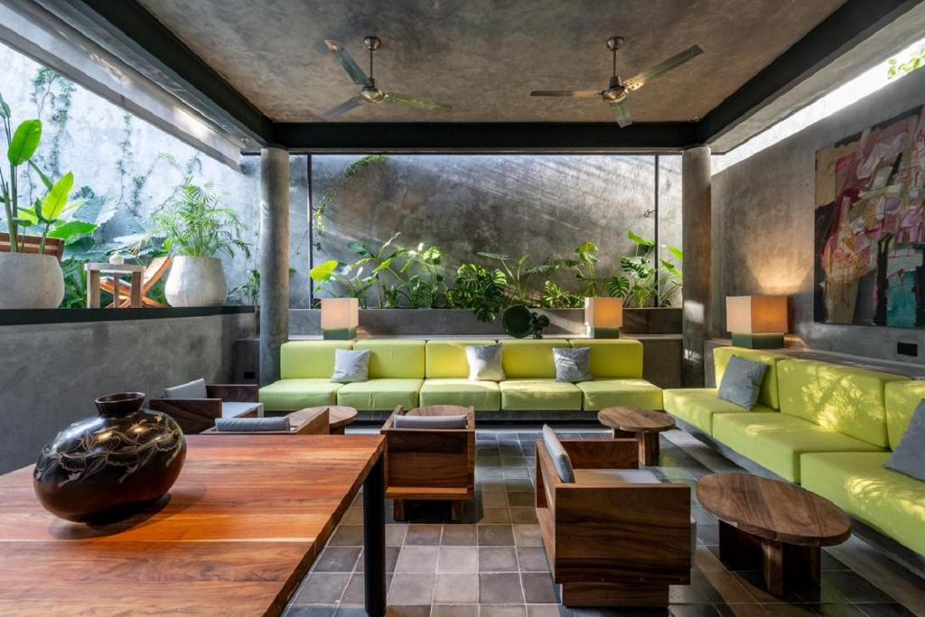 ein Wohnzimmer mit einer grünen Couch und einem Tisch in der Unterkunft Basico Pixoy Hotel in Valladolid