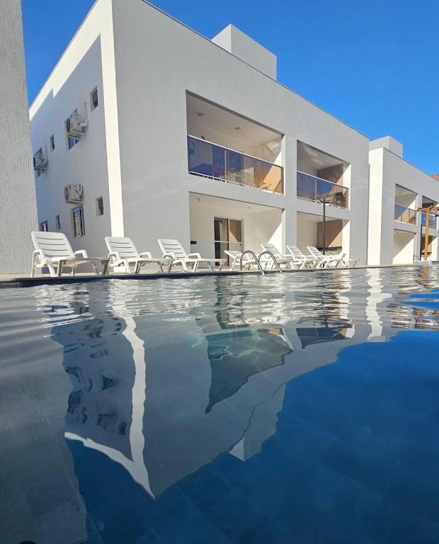 a white house with a swimming pool in front of it at Flat em Carapibus in Conde