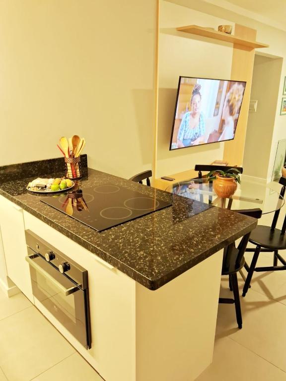 a kitchen with a black counter top and a table at Apartamento novo entre a praia dos Ingleses e Santinho in Florianópolis