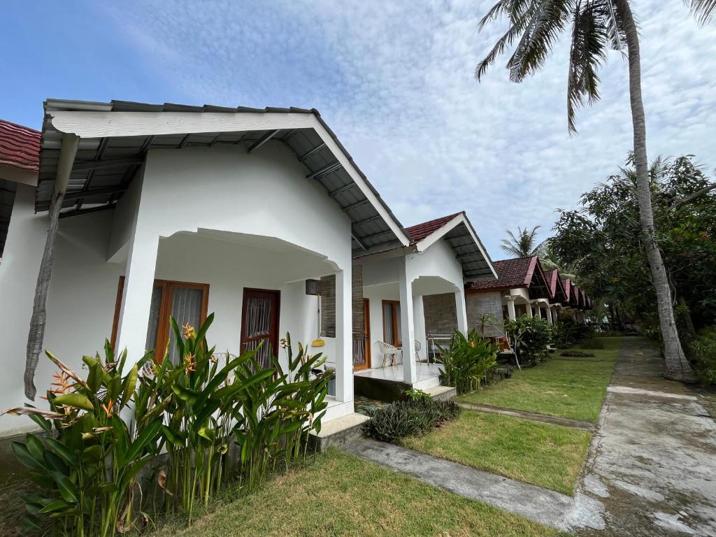 a row of white houses with a palm tree at Kuta Garden in Kuta Lombok