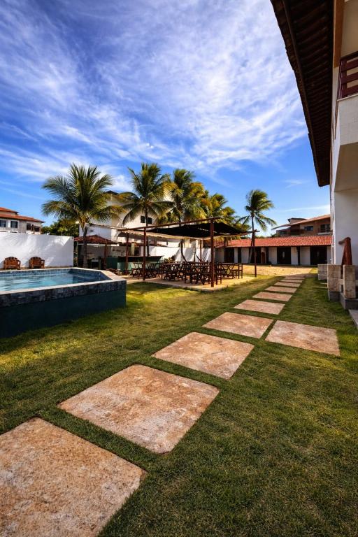 a resort yard with a swimming pool and palm trees at BRKITE Pousada in Cumbuco