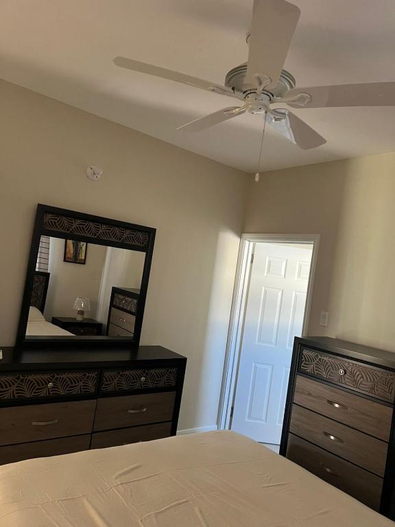 a bedroom with a ceiling fan and a dresser and a mirror at Gate home by ocean point in Lucea