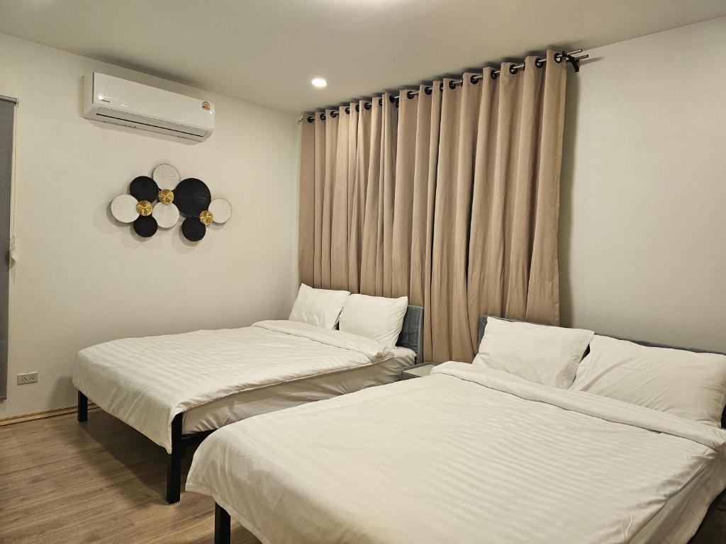 a room with two beds and a fan on the wall at Khiri&Kiwi homestay in Ban Mae Rim Nua