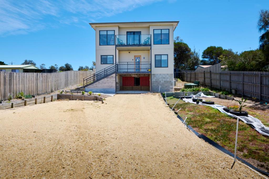 a house with a fence and a dirt yard at Wheeler's Paradise in Paradise Beach