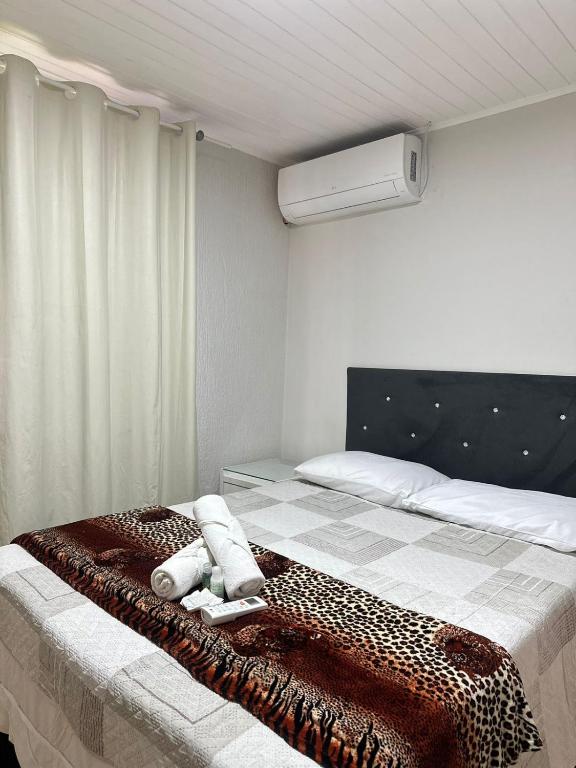 a bedroom with a bed with a cheetah blanket at Quarto Suíte Na grande Florianopolis in São José