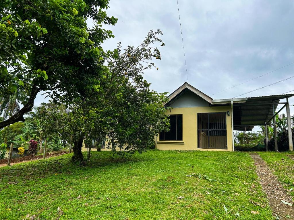een geel huis met een boom in de tuin bij Cabaña La Conquista in Sarapiquí