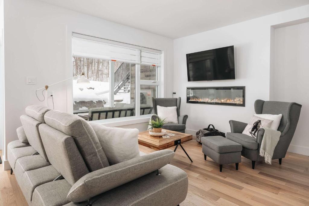 een woonkamer met een bank, stoelen en een tv bij Mont Blanc 121-111 in Saint-Faustin