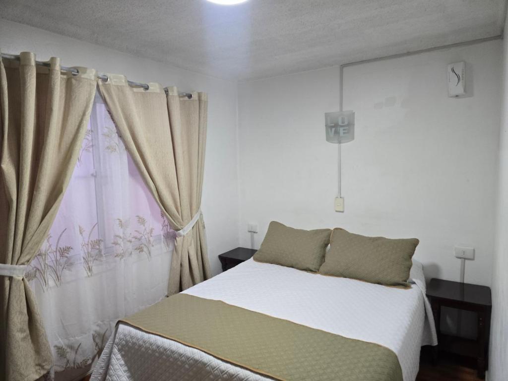 a white bedroom with a bed and a window at Andes Hostal Serena in La Serena