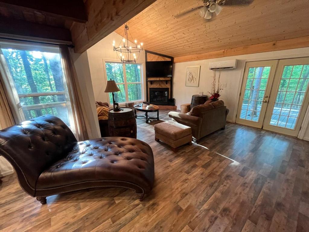 a living room with a leather couch and a chair at Cozy Cabin near KentuckyLake in Murray