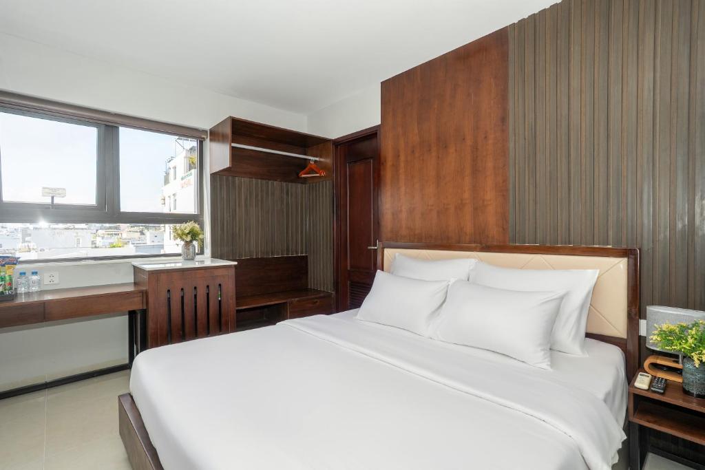 a bedroom with a large white bed and a kitchen at LUMIS TOURANE Hotel in Da Nang