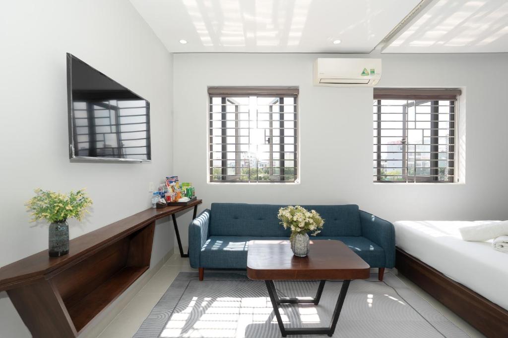 A bedroom sitting area with a blue sofa, coffee table, TV and windows beside the bed.