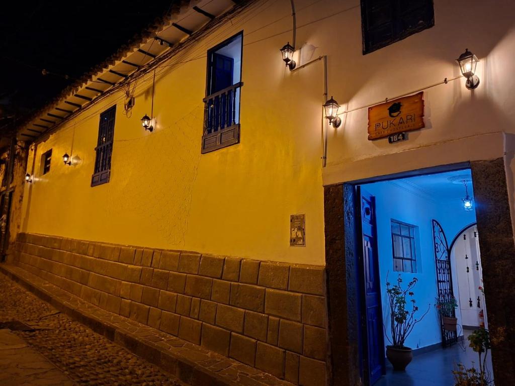 a yellow building with a door on a street at night at Pukari Hotel Cusco in Cusco