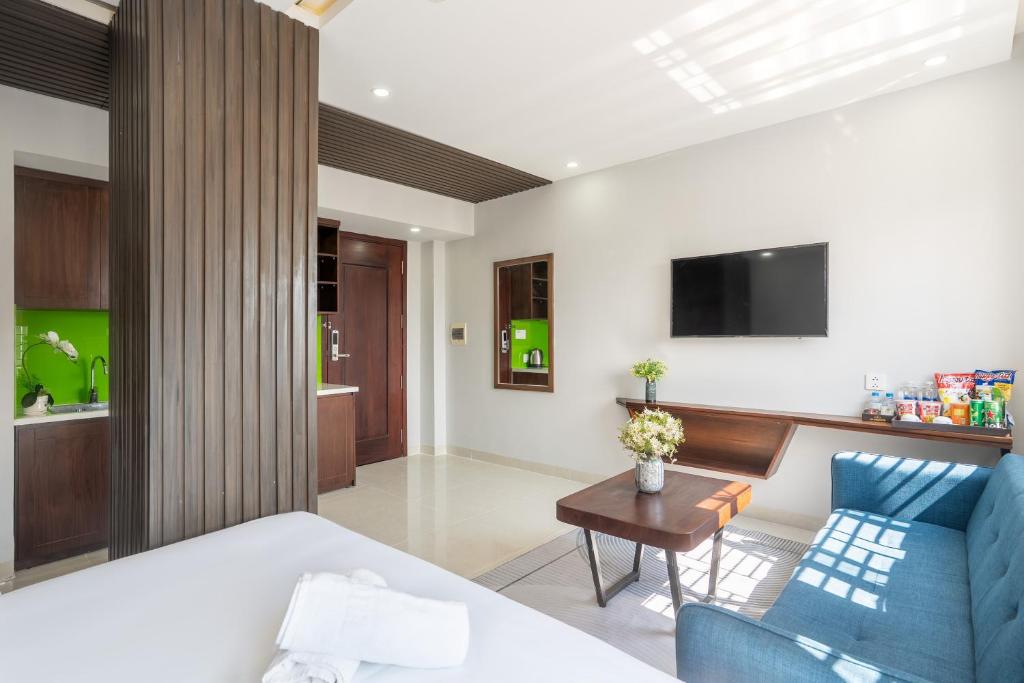A spacious-looking bedroom with a blue sofa, coffee table, TV and a partially screened entry area.