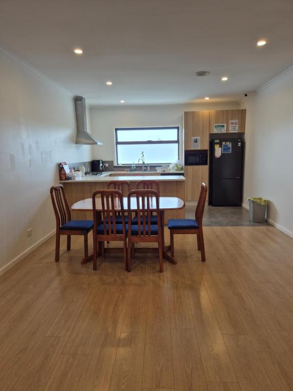 een keuken met een tafel, stoelen en een koelkast bij Sredna Homestay in Braybrook