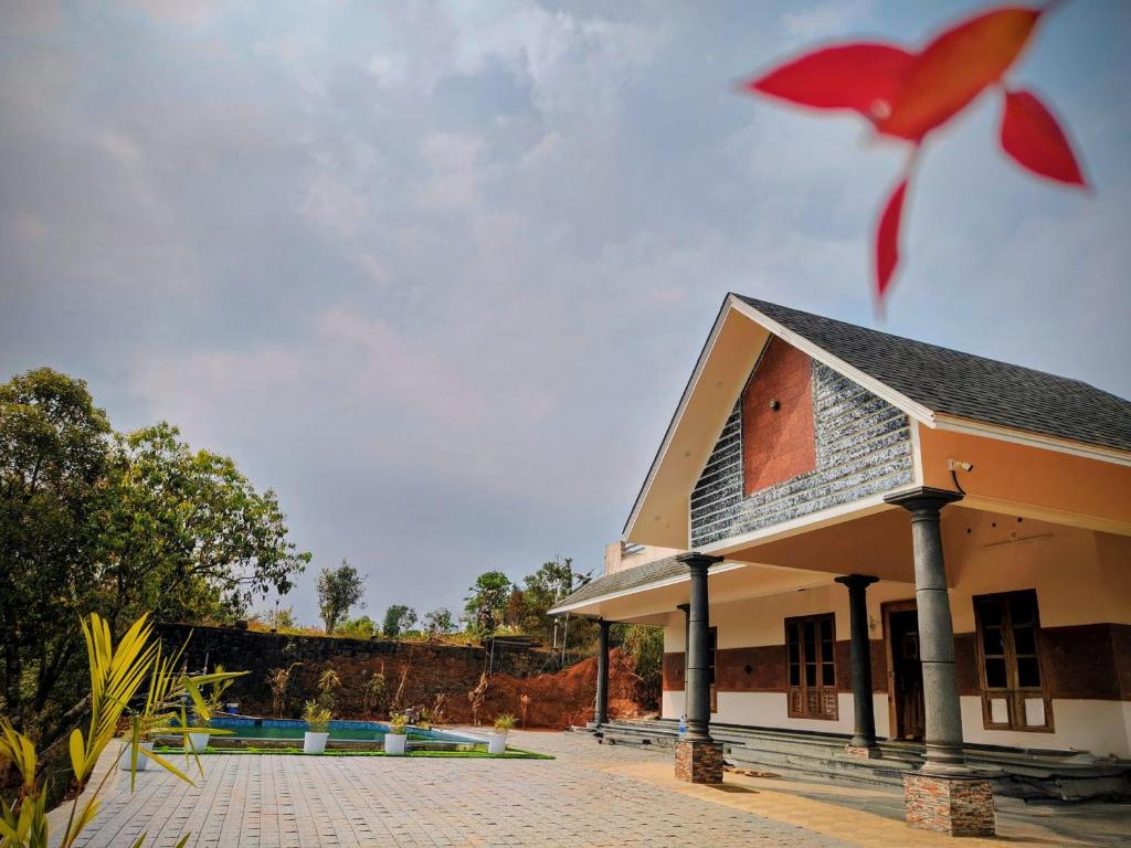 a building with a red flower in the foreground at Wantara Villa in Vagamon