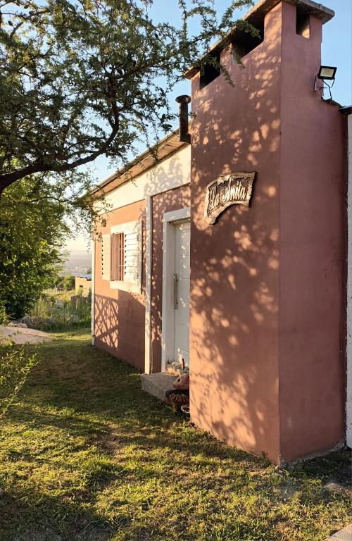 a pink building with a white door and a tree at Cabaña La Anita in Cosquín