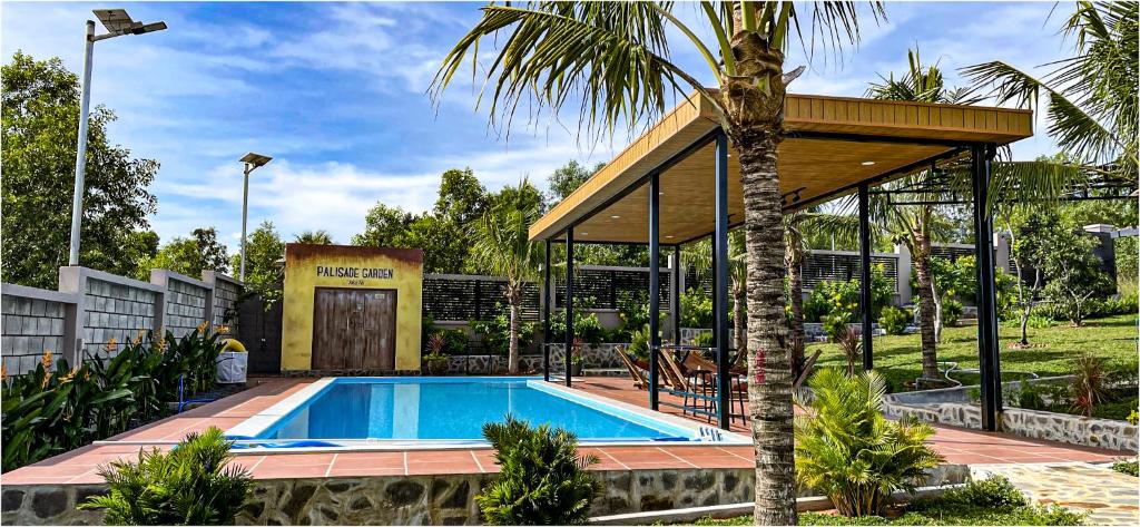 a swimming pool with a pavilion next to a palm tree at Palisade Garden in Ấp Thiện Sơn