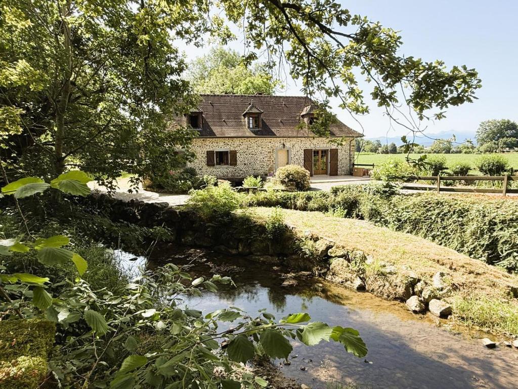 a stone house with a river in front of it at Moulin gratia in Lay-Lamidou