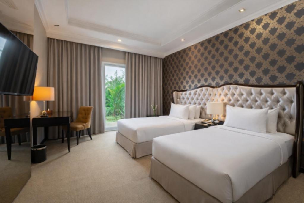 ein Hotelzimmer mit zwei Betten und einem Schreibtisch in der Unterkunft The Mirah Hotel Bogor in Bogor